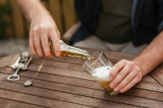 man pouring beer in glass cup for picnic